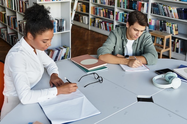 A student and a college advisor reviewing college application materials together in a brightly lit office, with college brochures scattered on the table.