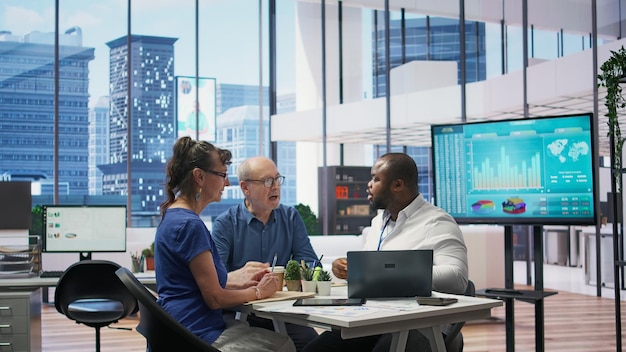 A vibrant shot of a data science team collaborating in a modern office, with diverse members analyzing complex datasets and visualizations on large monitors, while discussing strategies and insights around a table filled with laptops and coffee cups.